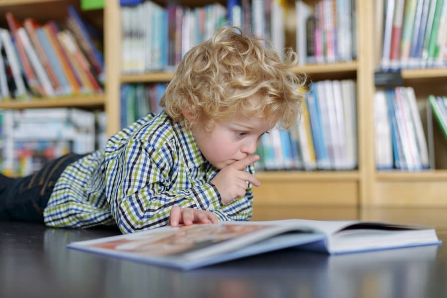 Blonde boy reading in a library
