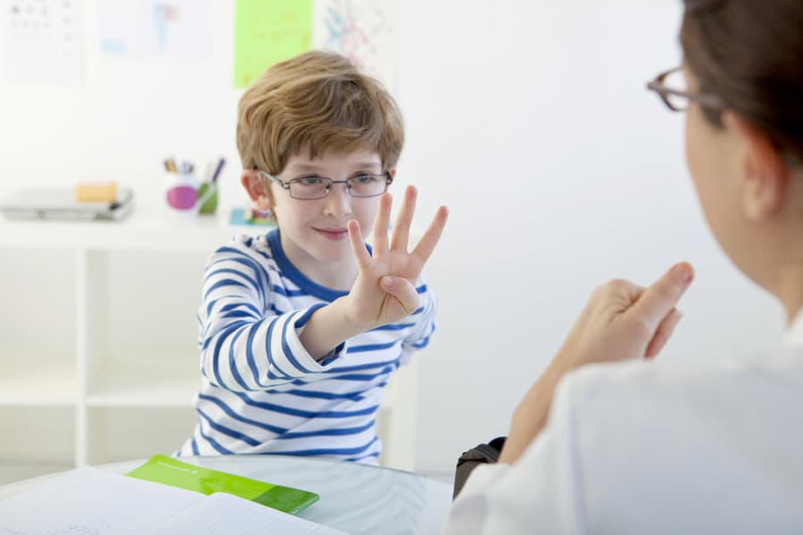 Child in speech therapy holding up three fingers