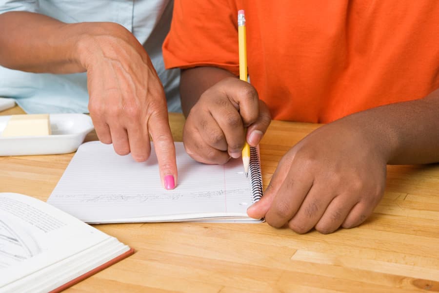 Adult and child hands writing together on paper